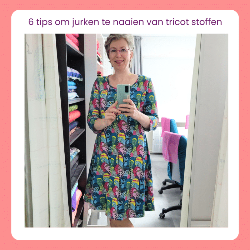 Linda in een tricot jurk, voor de spiegel in haar atelier, waar ze een selfie van zichzelf maakt.