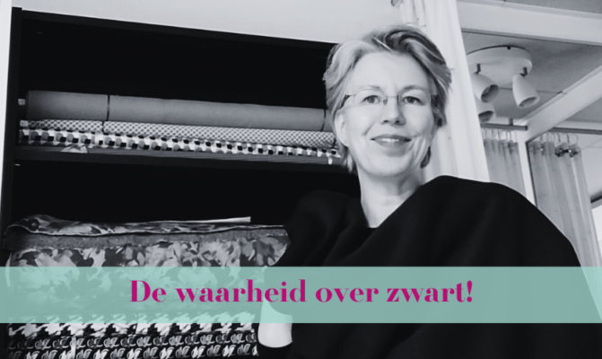 "Vrouw in modeatelier met kleurrijke stoffen op de achtergrond, terwijl ze zwarte stof vasthoudt."